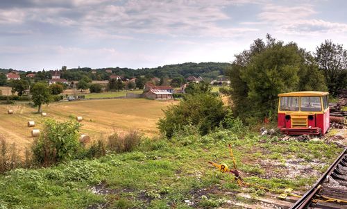 Train on railroad track amidst field against sky