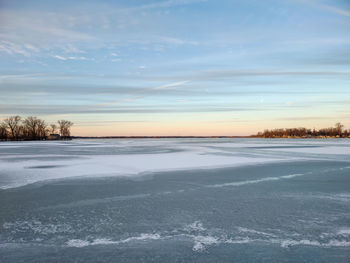 Snow covered landscape against sky during sunset