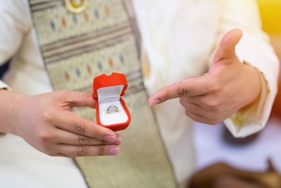 Midsection of bridegroom holding wedding ring during ceremony