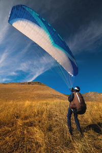 Paraglider is preparing to take off from a mountain on a sunny day. paraglider taking off from