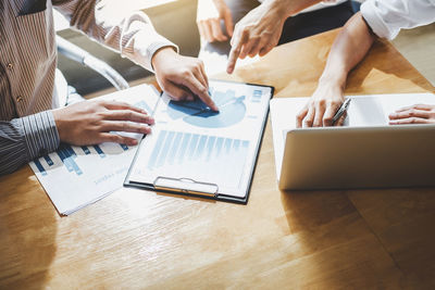 Midsection of businessman and colleague working over graph on table