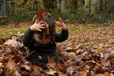 Baby boy playing with fallen autumn leaves in yard