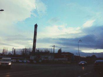 Cars on road against cloudy sky