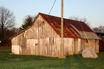 Wooden house on field against clear sky