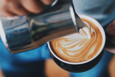 Midsection of man pouring milk on coffee cup