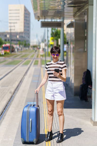 Rear view of woman using phone while standing in city