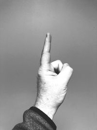 Cropped hand pointing against gray background