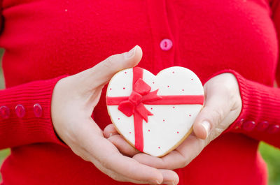 Close-up midsection of woman holding heart shaped cookie