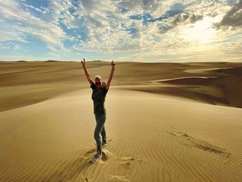 Full length of man walking on sand at desert against sky