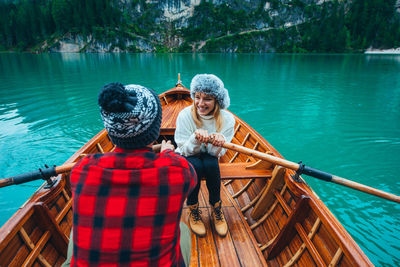 Smiling woman with man sitting in rowboat at lake