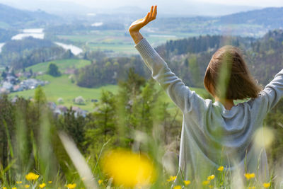 Side view of woman with arms outstretched standing against mountain