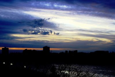 Silhouette cityscape against sky at sunset