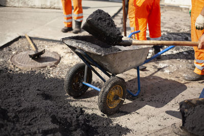 Repair of road. laying asphalt on road. worker in orange clothes. builders in summer in city.