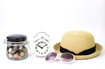 Close-up of alarm clock with coins and personal accessories against white background