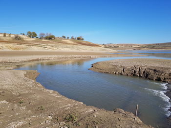 Scenic view of dike against clear blue sky