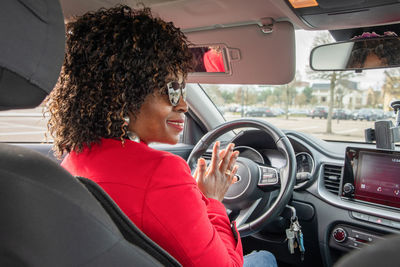 Pretty african american woman in car talking to neighbor in car while standing