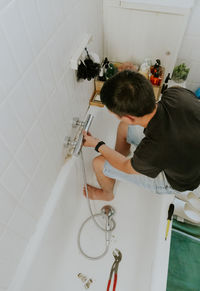 A young man removes the faucet in the wall with his hands.