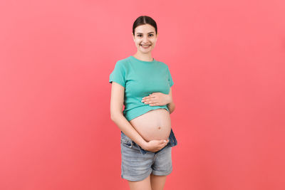 Portrait of a smiling young woman against red background