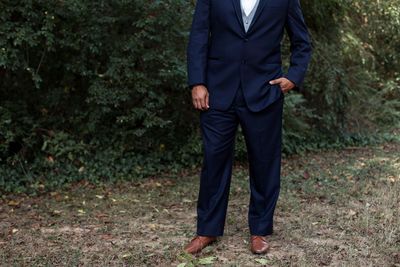 Low section of man in formalwear standing on field