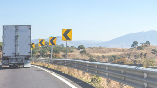 Road sign by mountain against clear sky