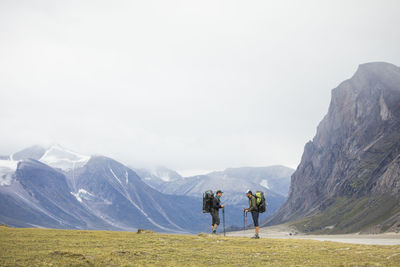 Two friends stop and discuss route during backpacking trip.