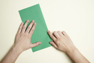Close-up of hand holding paper over white background