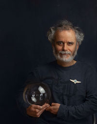 Colorful man with a curled beard silvery mustache holds a transparent glass ball in his hand