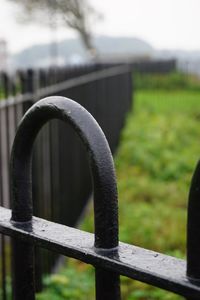 Close-up of railing against fence on field