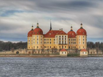 Building by river against cloudy sky