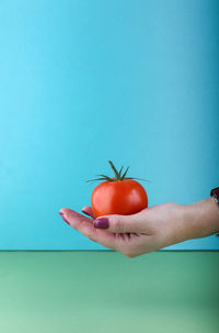 Hand holding apple against blue background