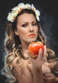 Close-up portrait of seductive woman holding apple