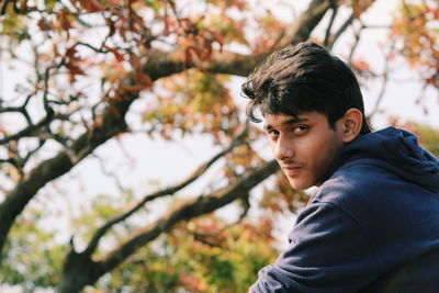 Portrait of smiling teenage boy against trees