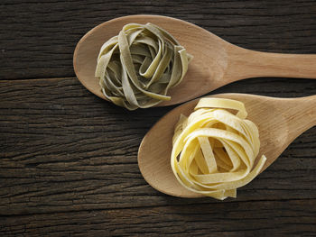 Close-up of tagliatelle pasta in wooden spoons on table