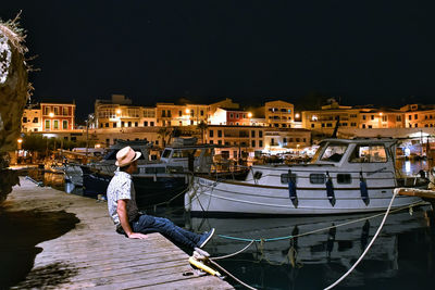 Woman standing on pier by canal against sky at night