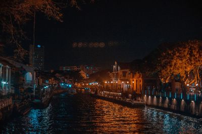 River amidst illuminated buildings in city at night