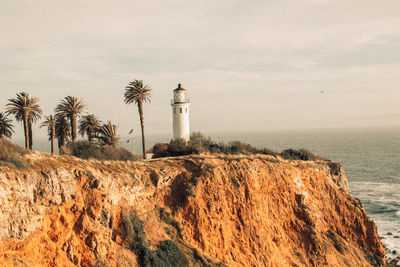 Lighthouse by sea against sky