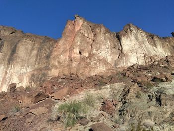 Low angle view of rocky mountains against clear blue sky