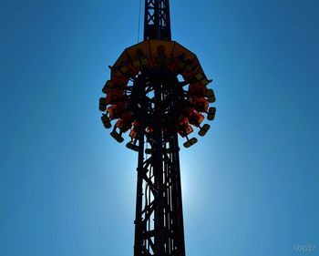 Low angle view of ferris wheel against clear blue sky