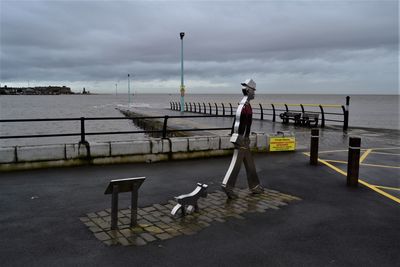 Metal sculpture with a grey cloudy sky and bad weather at the ferry slipway