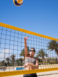 Woman playing volleyball at beach against sky