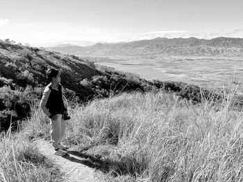 Rear view of woman walking on field against mountain