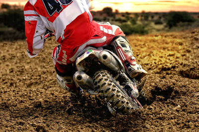 Low section of man riding motorcycle on dirt road