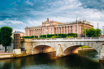 Arch bridge over river against historic building in city