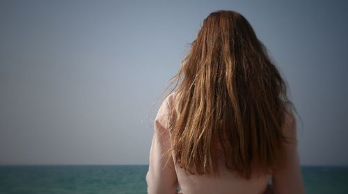 Rear view of man on beach against clear sky