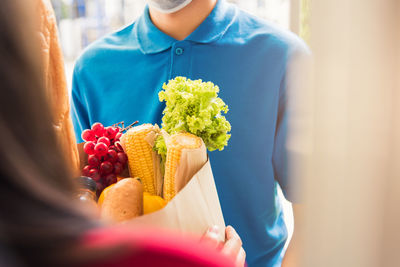 Asian young delivery man in uniform wear protective face mask he making grocery