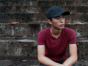 Thoughtful young man looking away while sitting on steps