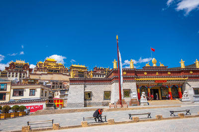 People outside historic building against blue sky