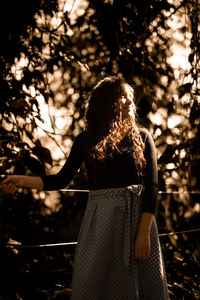 Rear view of woman standing by tree