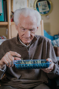 Smiling man holding seedlings in tray at home