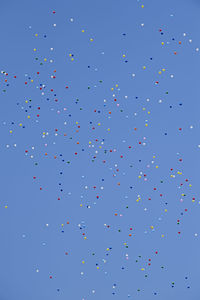 Low angle view of balloons flying against blue sky